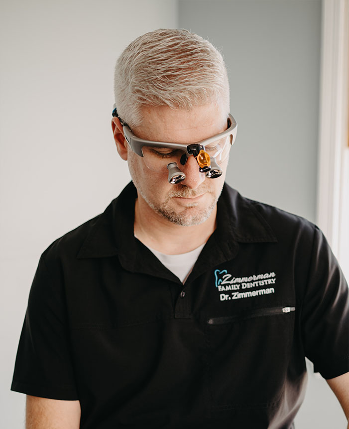 The image features a person wearing glasses and a black shirt, standing in front of a mirror with a reflection showing them looking down.