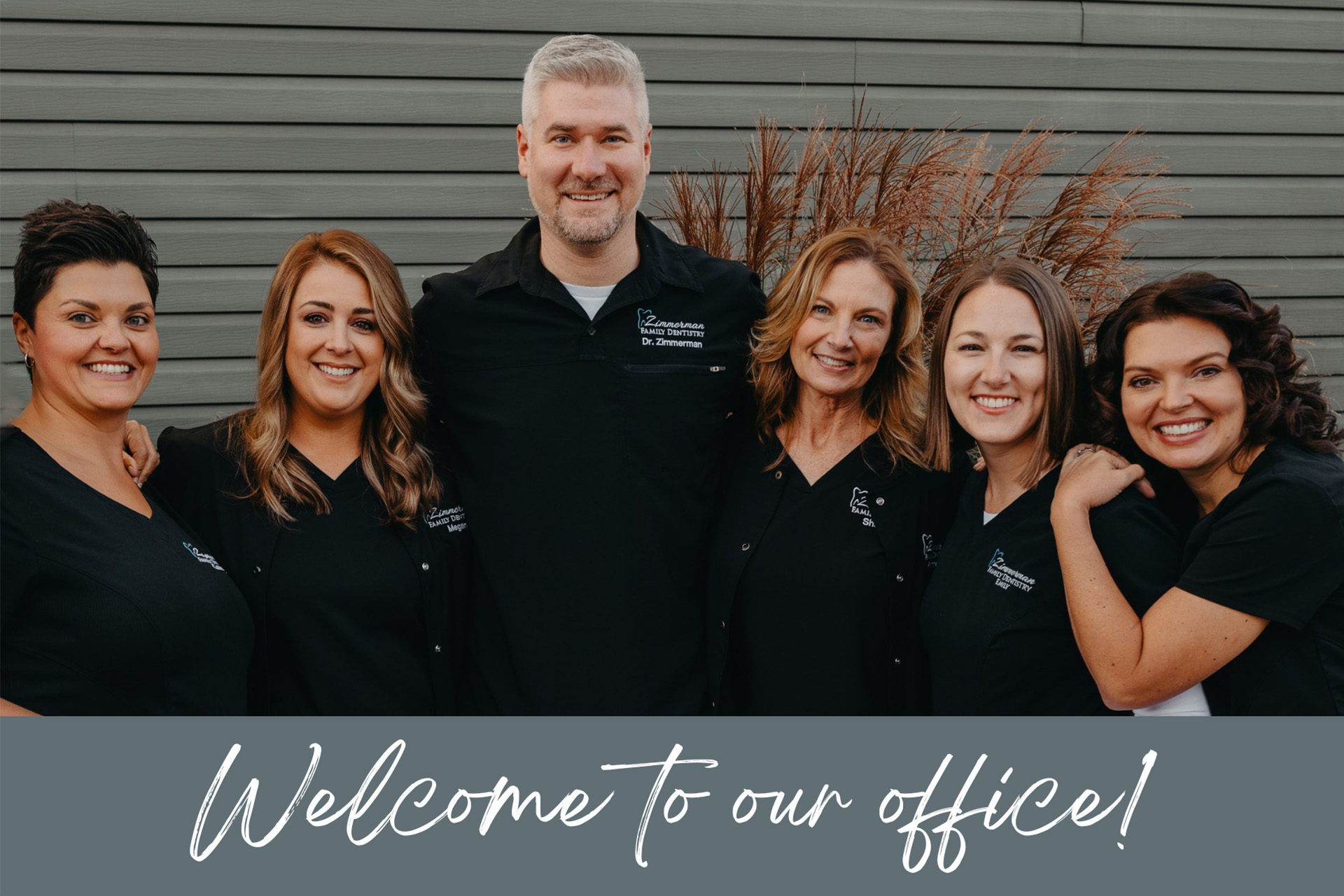 The image shows a group of individuals, likely professionals given their attire and the setting, posing for a photo. They are standing in front of a building with a sign that reads  WELCOME TO OUR OFFICE.  The text overlay on the image includes the words  Welcome to our office  and  OFFICE,  which suggests that this is an advertisement or announcement about the location of their business.