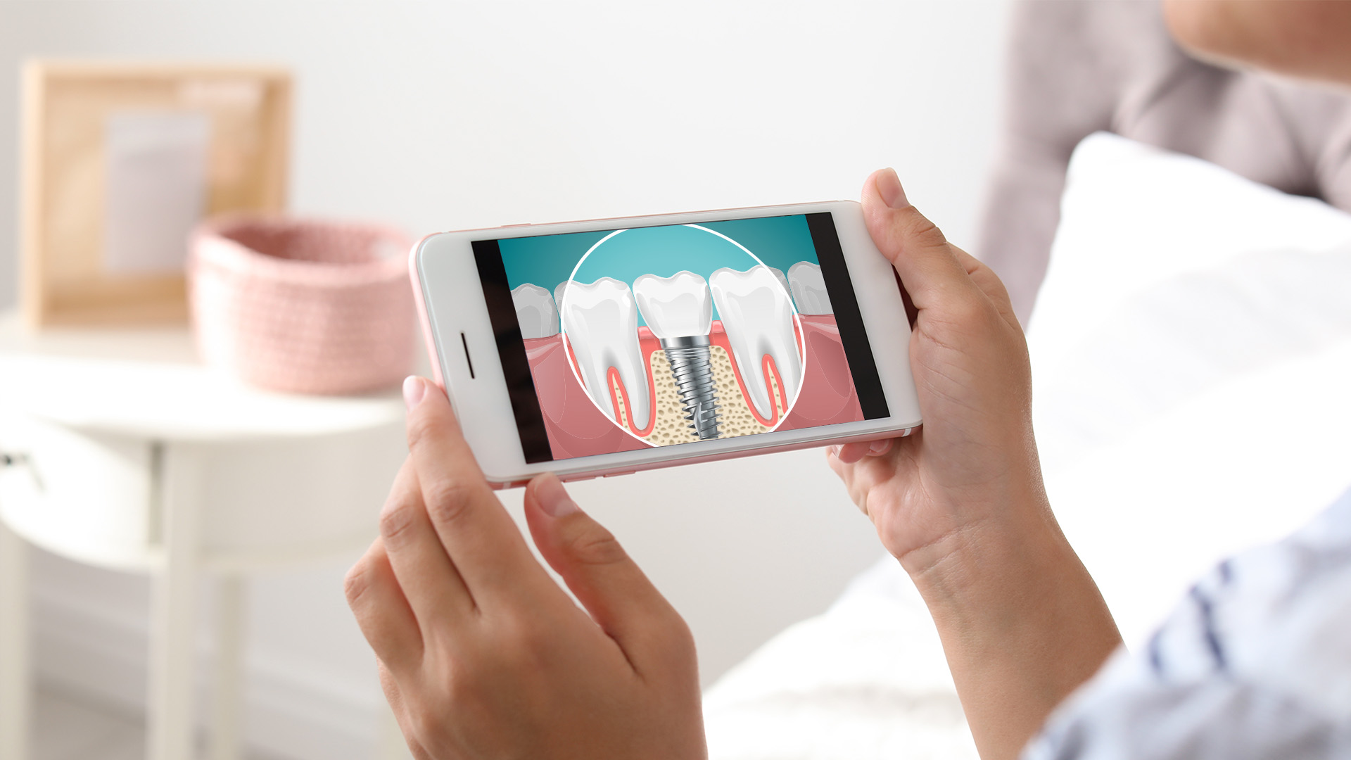 The image shows a person holding a smartphone with a graphic of a tooth and gums on the screen, likely demonstrating dental care or oral health.