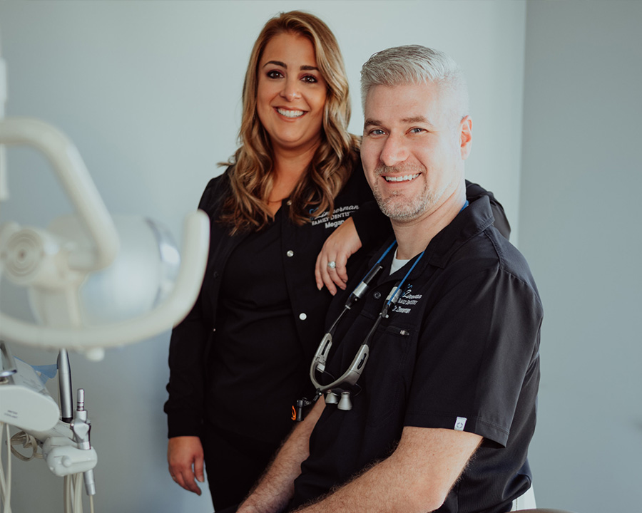 The image shows a man and a woman in a dental office setting, with the man wearing a black shirt and the woman in a white top.
