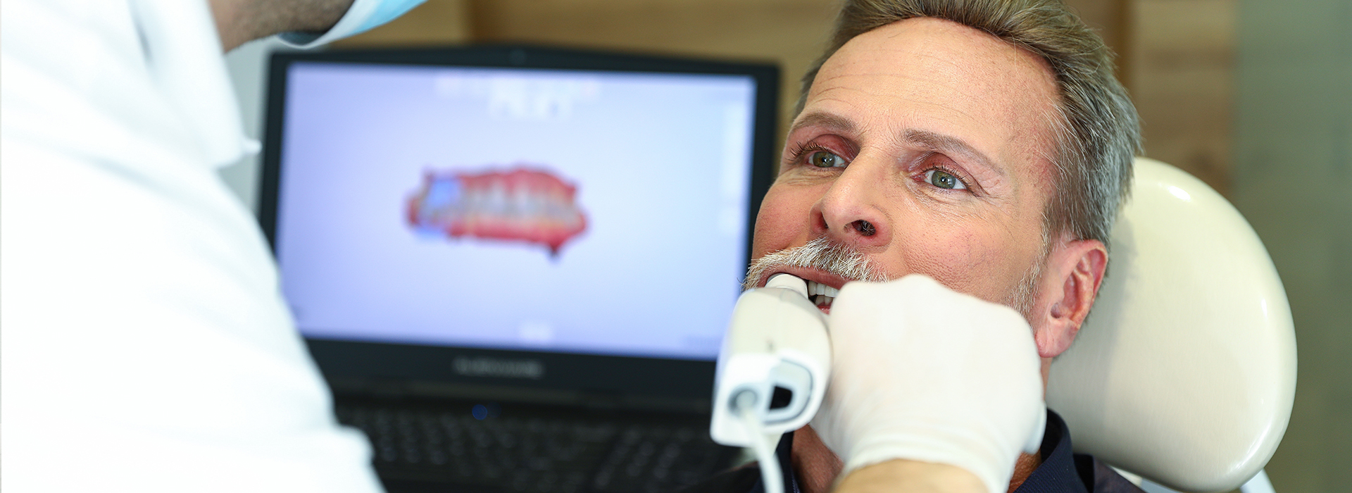 A man receiving dental treatment from a professional in an office setting.