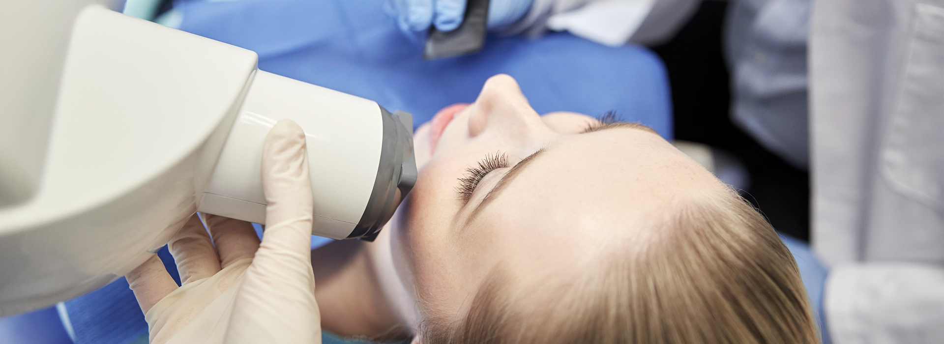 A person receiving a dental implant procedure with the dentist using a microscope to guide the placement.