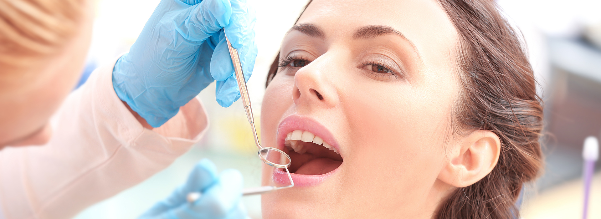 A close-up photo of a dental professional performing a dental procedure on a patient, with the focus on precision and care.