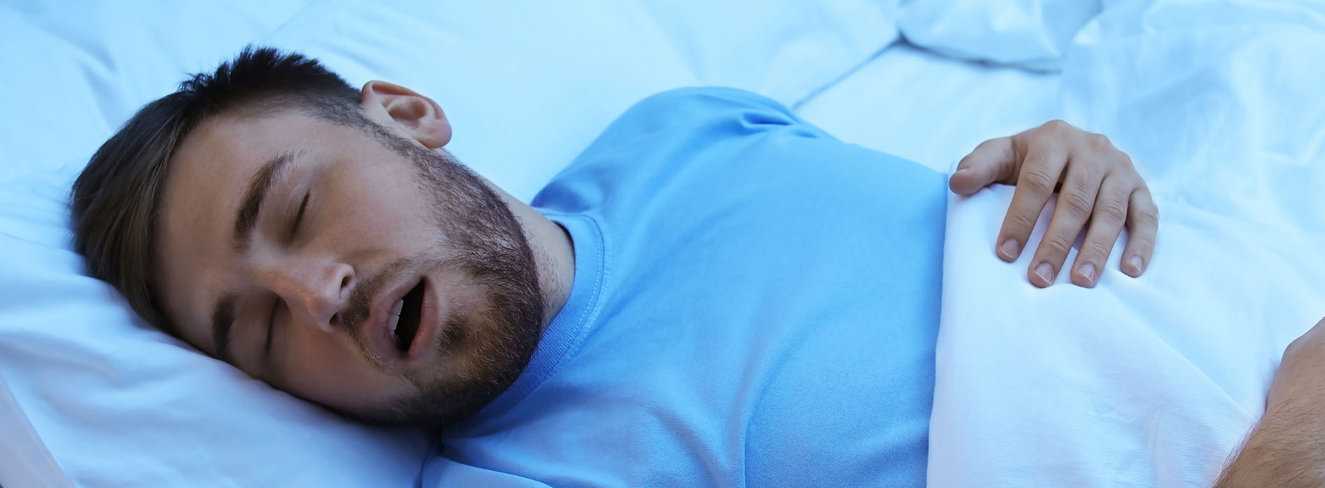 The image shows a man lying in bed with his head resting on a pillow, appearing to be asleep or in a relaxed state.