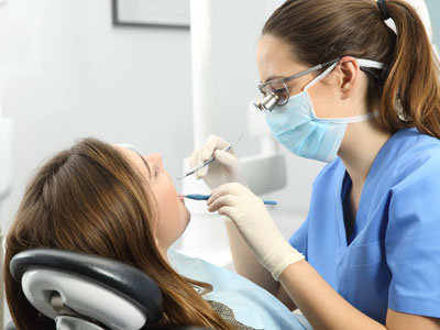 An image of a dental professional performing a procedure on a patient in a clinical setting.