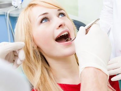 A woman in a dental chair receiving dental treatment, with a dentist performing the procedure.