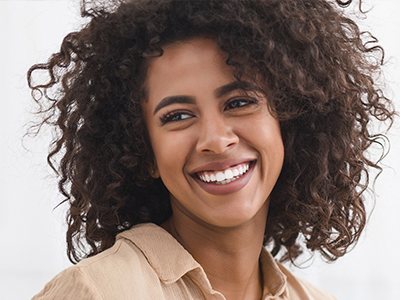 The image shows a person with curly hair and a smile, looking directly at the camera.